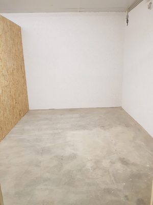 Leere Lagerbox mit Betonboden und weißen Wänden